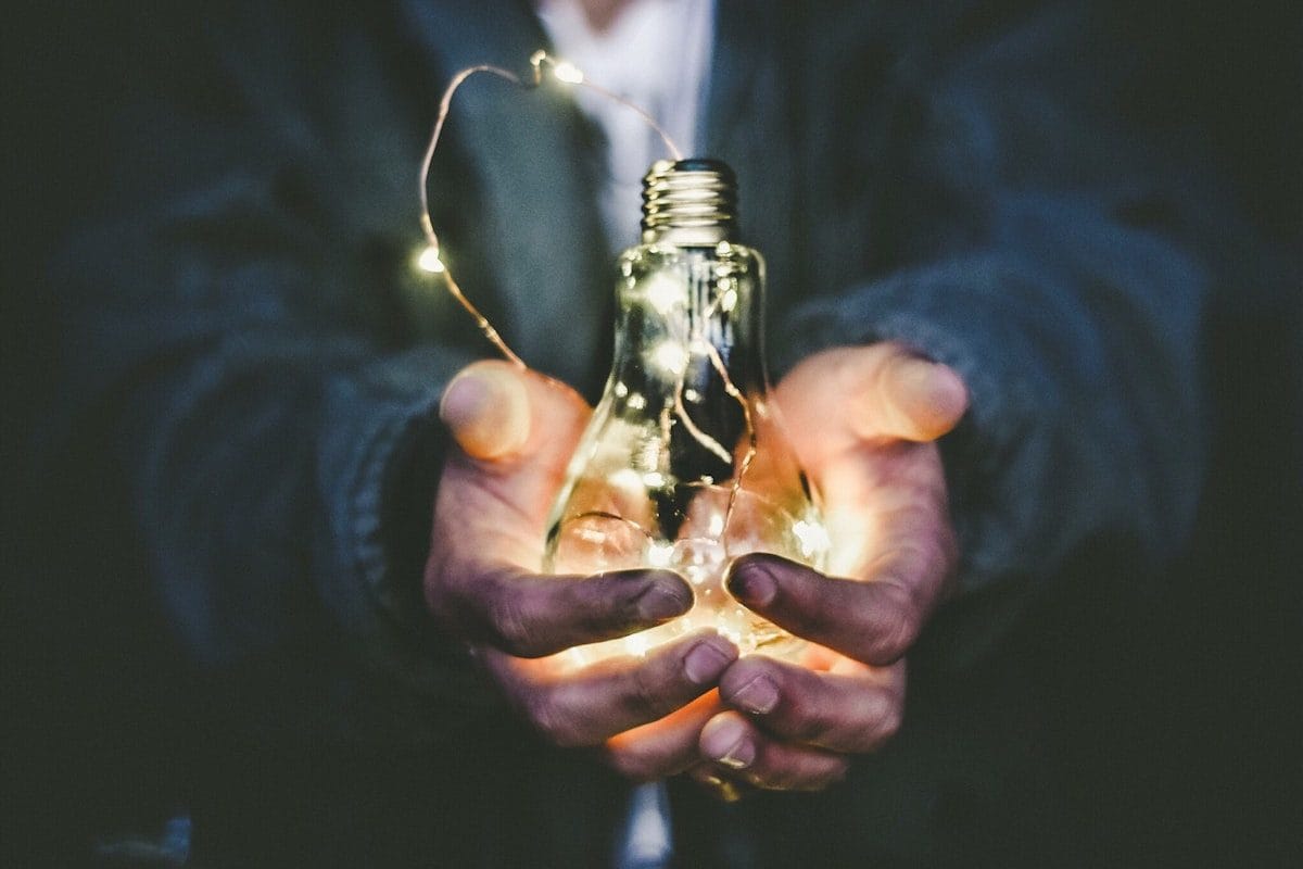 Hands holding a glowing lightbulb — representing finding the insight and growth inside failure