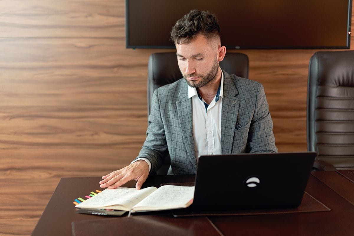 Professional reviewing notes and a laptop while researching a company before an interview