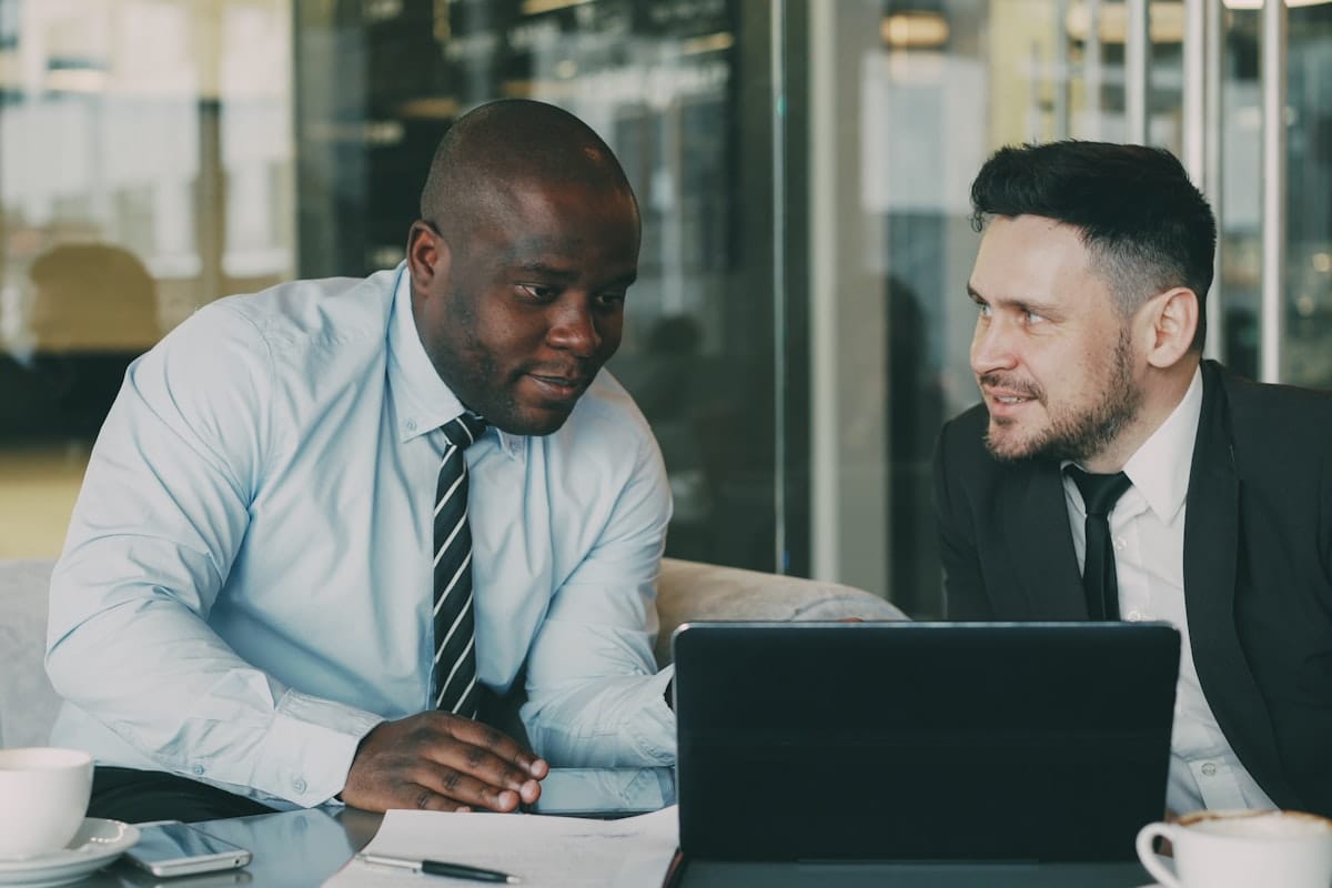 Two consulting professionals discussing over a laptop in a glass-walled office