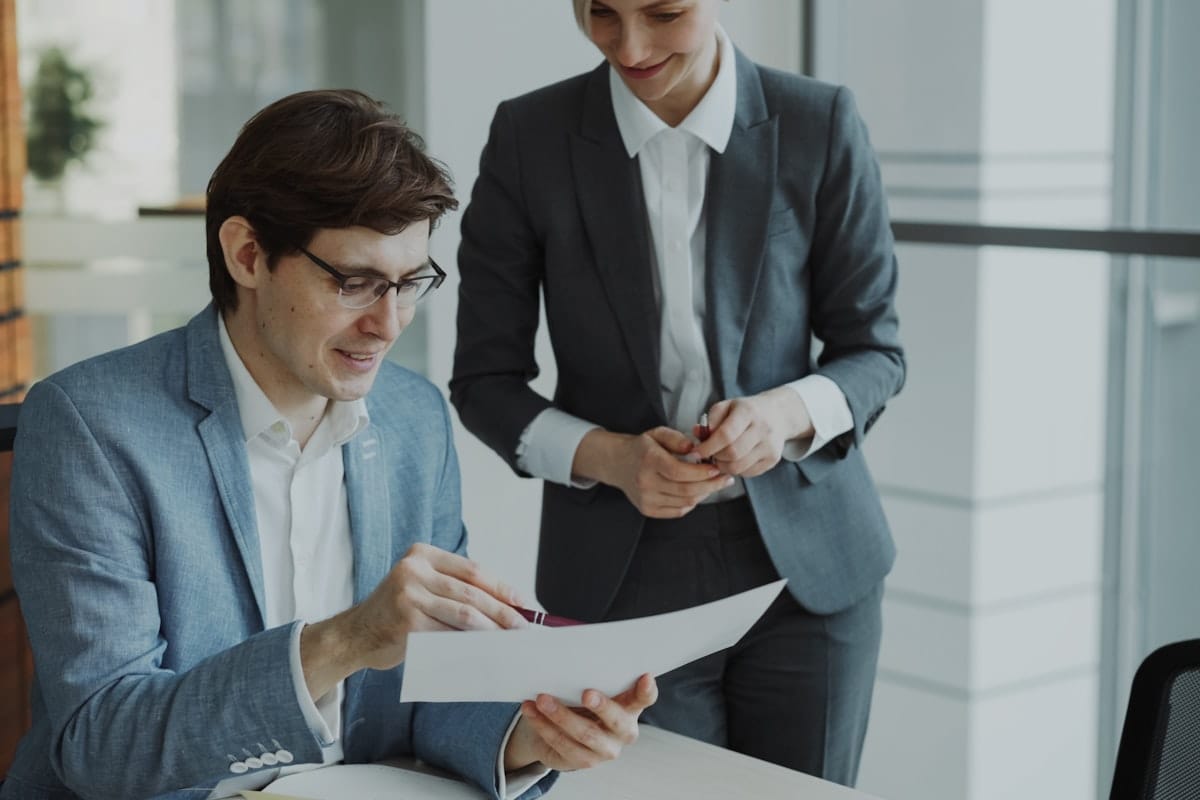 Two finance professionals reviewing a document together in a bright modern office