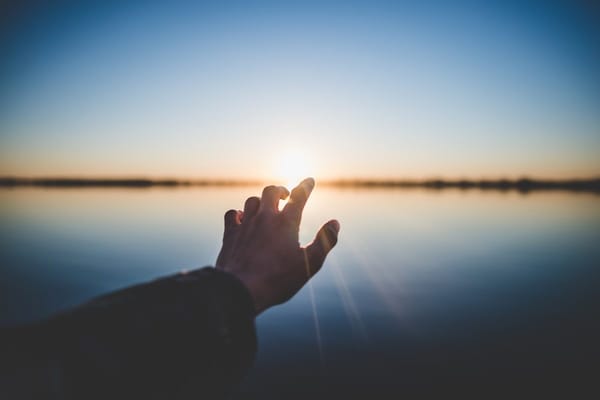 Hand reaching toward light on the horizon — representing the clarity of knowing and presenting your strengths