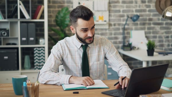 A professional calmly working at a desk amid a busy office: composure that comes from having a method, not a personality trait