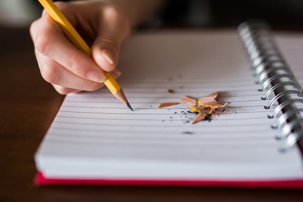 A hand poised with a pencil over a blank notebook: the forward-looking planning this question rewards