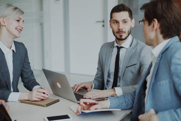 Marketing professionals discussing a campaign around a laptop in a modern office meeting