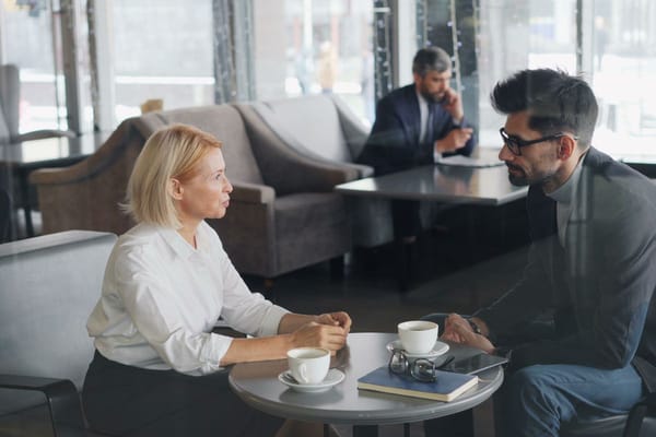 Two colleagues in conversation across a table during a work discussion about a decision